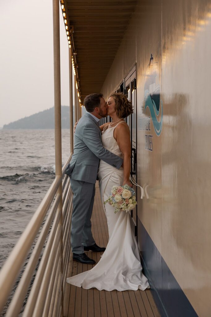 Husband kisses wife on a boat at a lake in Idaho after they elope in Idaho