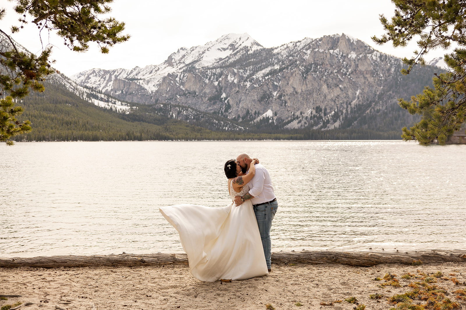 Couple kissing by a mountain lake with sweeping views in one of the best places to elope in Idaho.