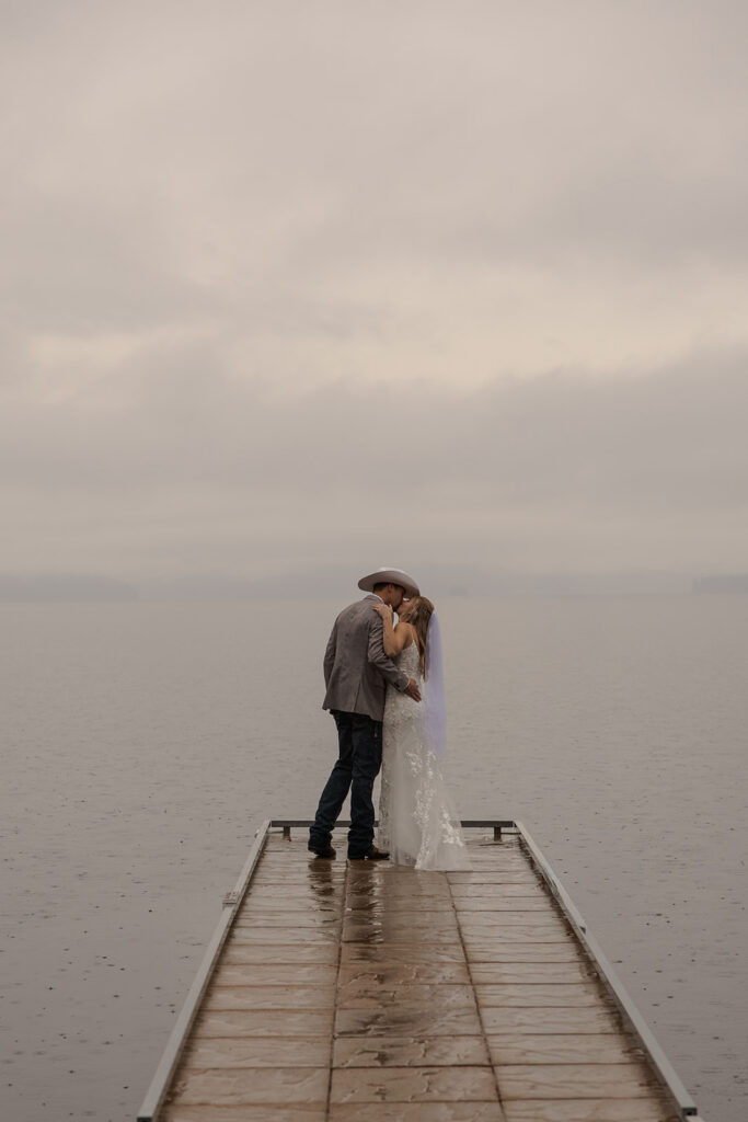 Idaho Elopement Locations | Love in the Hills Photo & Video Newlyweds embracing at the end of a dock with peaceful Idaho elopement locations all around.