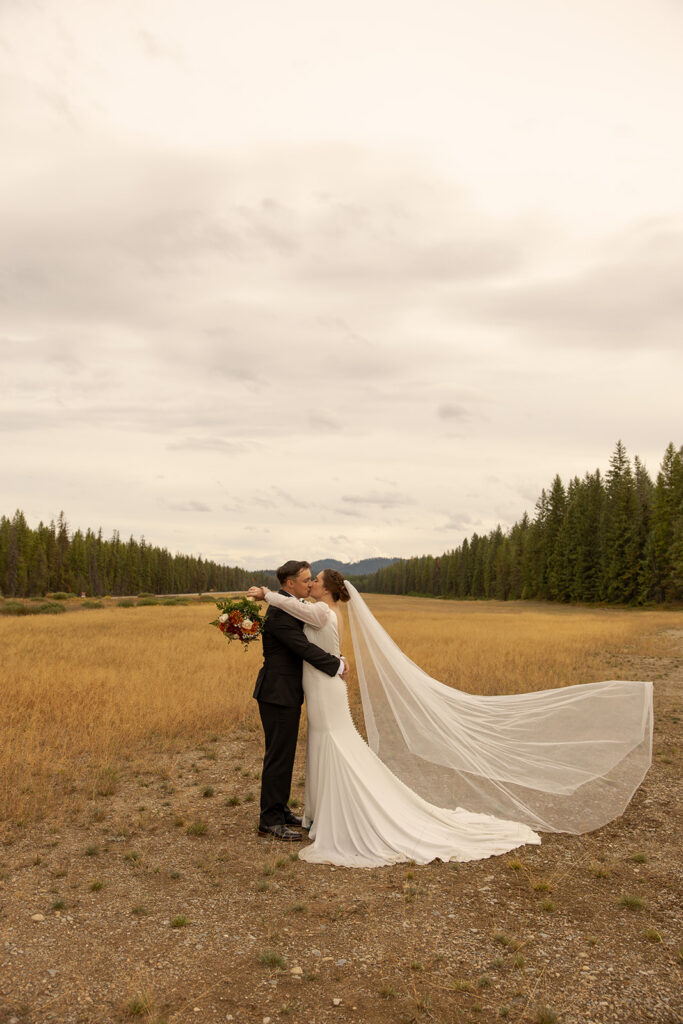 Places to Elope in Idaho | Love in the Hills Photo & Video Couple kissing in an open field surrounded by mountains in one of the best places to elope in Idaho