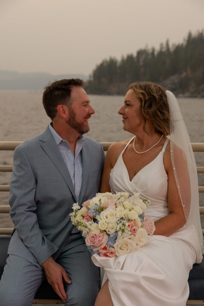 Places to Elope in Idaho | Love in the Hills Photo & Video Bride and groom sitting by the water on their elopement cruise in one of the most scenic places to elope in Idaho.