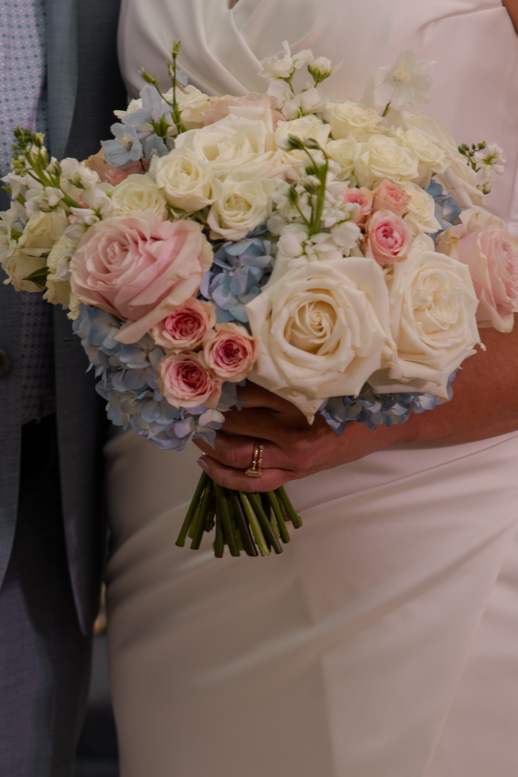 Bride holds her wedding bouquet of pink, blue, and white flowers at her elopement in Idaho