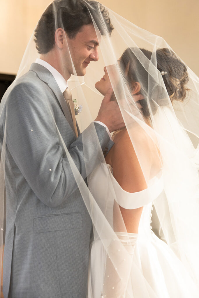Husband and wife look at each other lovingly under a veil during their elopement in Idaho