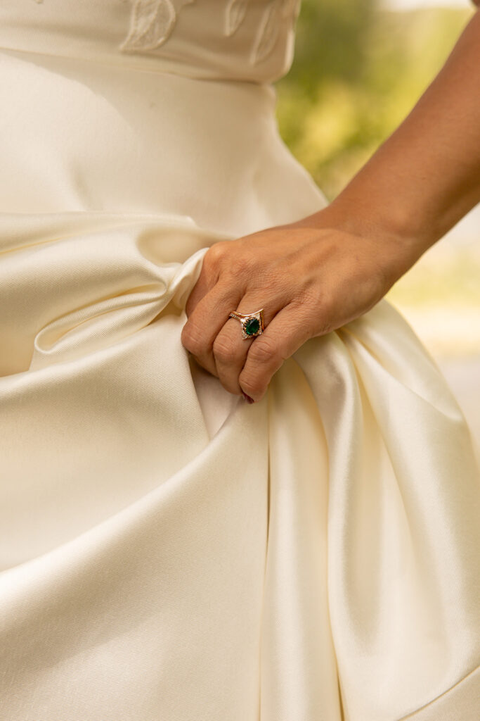 Bride holds her wedding dress and shows off her green wedding band at her elopement in Idaho