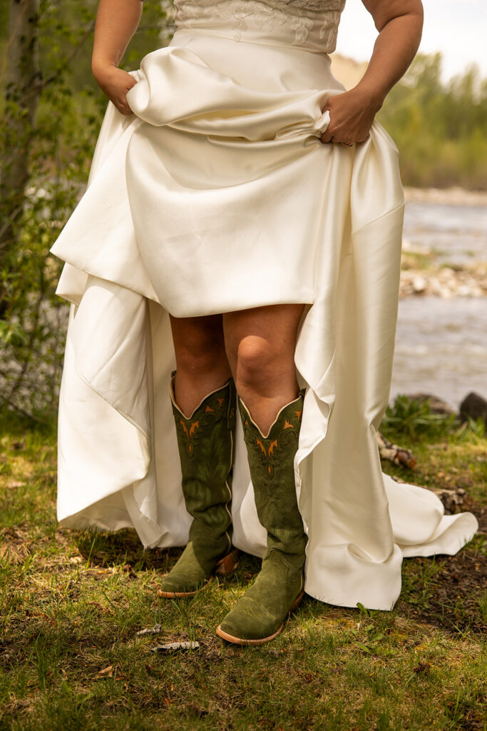 Bride shows off her green cowgirl boots under her wedding dress during her Idaho elopement