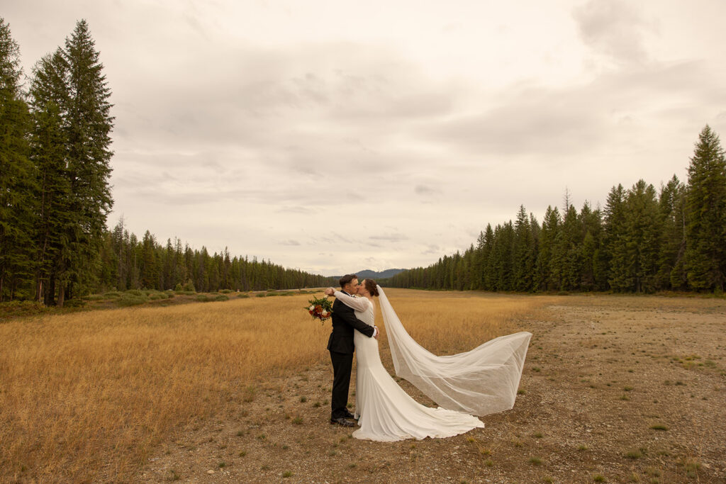 Priest Lake Wedding | Love In The Hills Photo And Video Bride and groom sharing a kiss with a flowing veil during a Priest Lake Idaho wedding portrait.