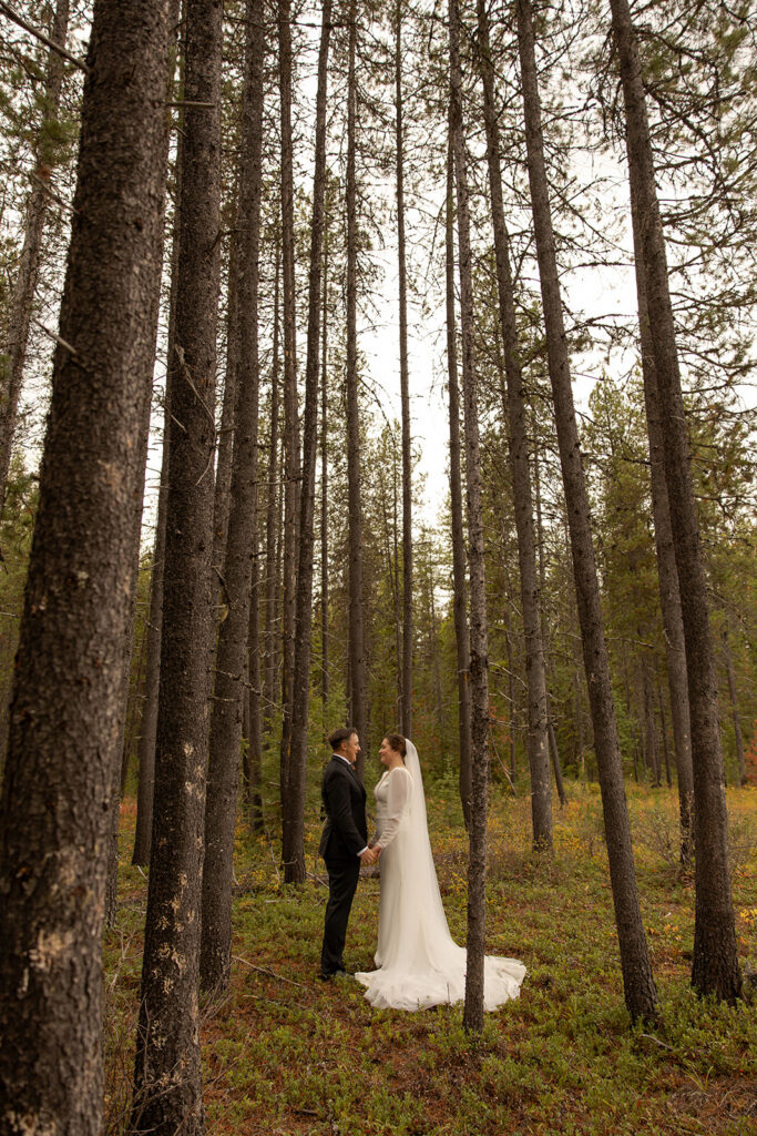 Priest Lake Wedding | Love In The Hills Photo And Video Bride and groom standing among the pine trees after their Priest Lake wedding ceremony.