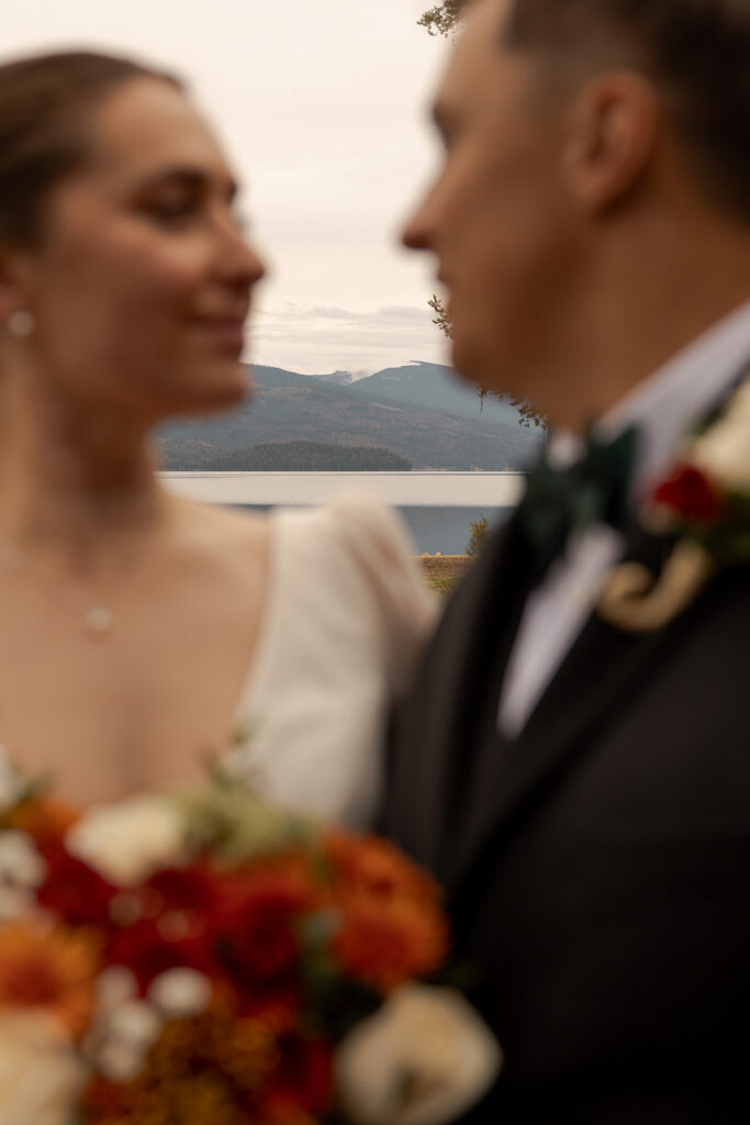 Bride and groom embracing with Priest Lake in the background during their Priest Lake wedding